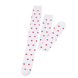 Detailed view of white over-the-knee socks with red heart patterns on white backdrop