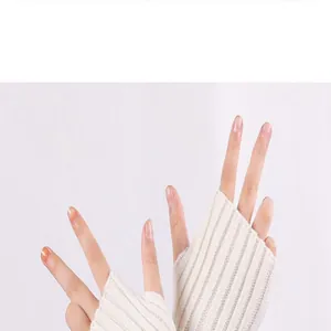 Close-up view of soft cream ribbed knitted fingerless arm warmers on hands making V signs.