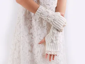 Close-up of cream knitted fingerless gloves with elegant lace trim and hollowed leaf pattern