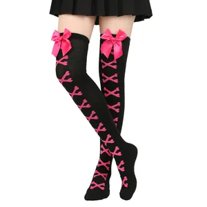 Vue détaillée de chaussettes hautes noires avec nœuds roses et motifs d'os roses