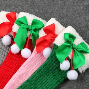 Detail of colorful knitted Christmas leg warmers with satin bows and soft pom-poms.