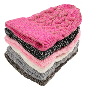 Close-up of stacked colorful cable knit beanies showing detailed wool texture