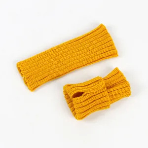 Close-up of yellow knitted fingerless arm warmers showing the ribbed texture and thumb hole.