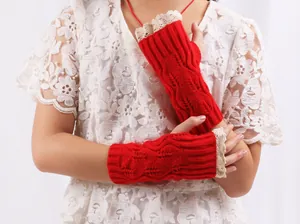 Close-up of red knitted fingerless gloves featuring elegant cream lace trim detail