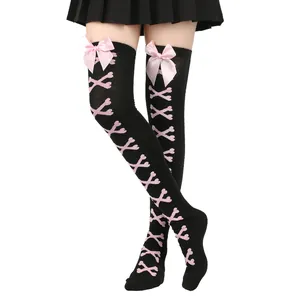Détail des chaussettes hautes noires avec nœuds roses et motif de laçage en os