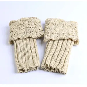 Detailed view of beige knit leg warmers with textured hollow pattern and fold-over cuff design
