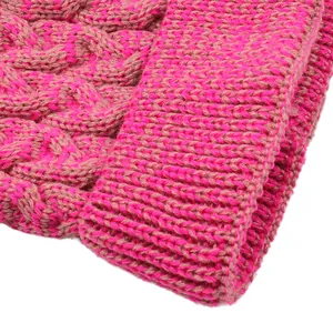 Close-up detail of a pink and tan cable knit beanie hat showing texture