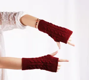 Detail van rode kabelgebreide vingerloze handschoenen voor winterse warmte en zachtheid.