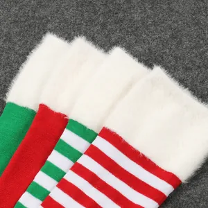 Detalle de calcetines altos de Navidad a rayas rojas y verdes con ribete de pelo