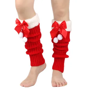 Detailed view of red knitted Christmas leg warmers featuring white fur trim and red bows