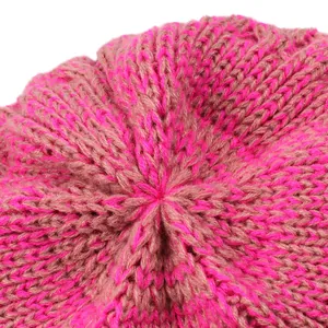 Detailed close-up showing the crown stitching of a pink and brown knitted winter beanie