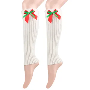 Close-up of white knitted Christmas leg warmers with plush lining and festive bow