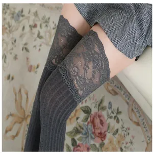 Detail view of grey knitted thigh-high socks featuring delicate lace trim