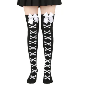 Détail de chaussettes hautes noires gothiques avec motifs d'os croisés et nœuds blancs