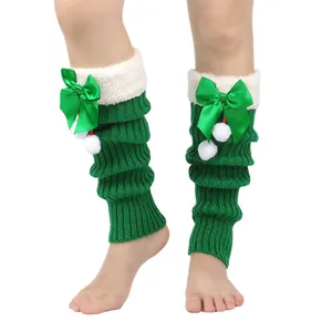 Detail shot of green Christmas knit leg warmers with white plush trim and bows