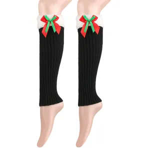 Close-up of black knit leg warmers with plush white trim and a festive Christmas bow
