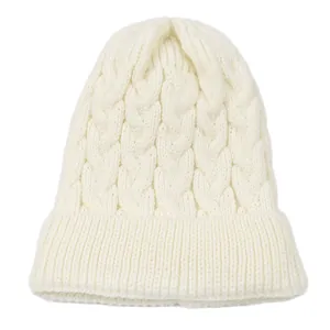 Close-up detail of white cable-knit beanie hat showing soft texture and cozy winter pattern