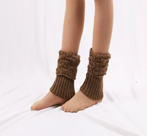 Close-up of brown knitted short leg warmers with cable knit and ribbed patterns