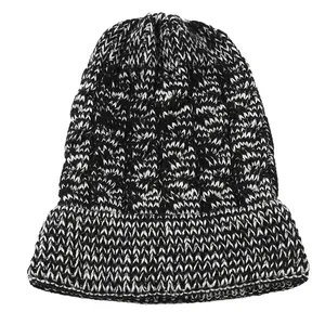 Detailed macro view of the thick black and white cable knit texture on a winter beanie.
