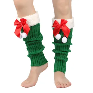 Detail of green knitted Christmas leg warmers with red bows and plush white fur trim