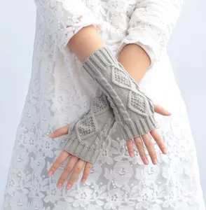 Close-up of grey cable knit fingerless gloves showing intricate texture and weave.