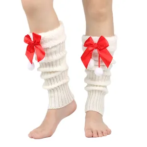 Detailed view of white knitted leg warmers featuring red satin bows and soft plush pompoms