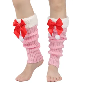 Close-up of pink ribbed leg warmers with red satin bows and white pom-pom detail