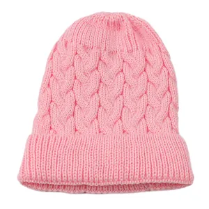 Close-up of pink cable-knit beanie showing soft texture and warm braided pattern.