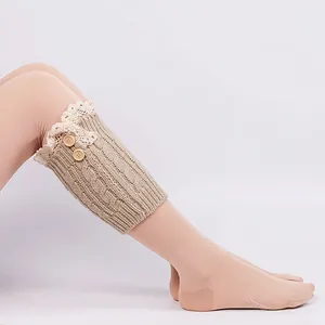 Close-up detail of beige knitted leg warmer featuring lace trim and vintage wooden buttons.