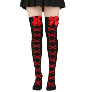 Vue détaillée de chaussettes hautes noires avec nœuds en satin rouge et motifs d'os