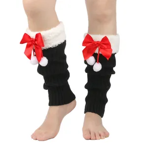 Detail view of black knitted leg warmers with white faux fur trim, red satin bows and pom-poms