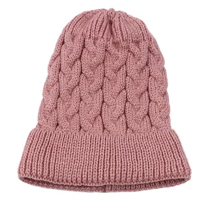 Close-up of pink cable knit beanie showing thick warm texture and ribbed cuff.