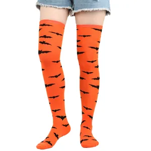 Detailed view showing the black bat pattern on orange over-the-knee Halloween stockings.