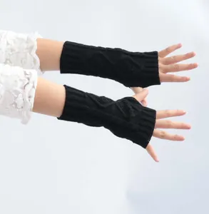 Macro detail of black cable-knit fingerless gloves showing the textured knit pattern on arm
