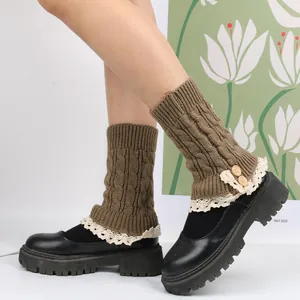 Close-up of brown cable knit leg warmers with cream lace trim and decorative wooden buttons
