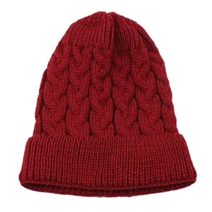 Macro detail of red cable knit beanie hat showing thick texture and ribbed cuff for winter