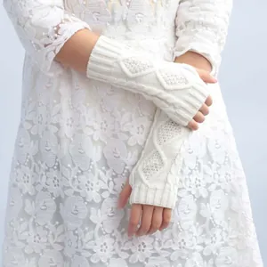 Close-up of elegant white cable-knit fingerless gloves styled with a lace dress.