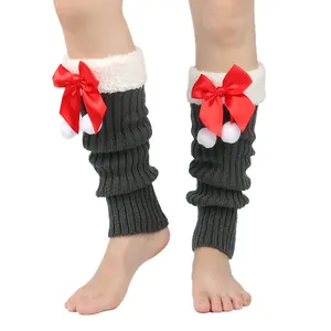 Detailed view of grey knitted leg warmers with festive red bows and white plush pompom trim