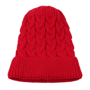 Close-up detail of a red cable-knit beanie with soft texture and classic pattern