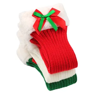 Detail of Christmas knitted leg warmers with plush cuffs and festive bows.