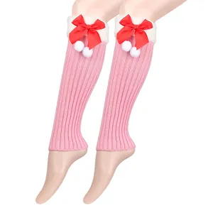 Soft pink knitted leg warmers decorated with festive red bows and white pom-poms