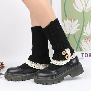Close-up of black knit leg warmers with white lace trim and decorative wooden buttons.