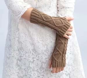 Macro view of brown cable knit fingerless arm warmers featuring a stylish diamond pattern.