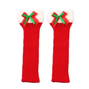 Close-up of red knitted Christmas leg warmers with white fur trim and ribbon bows