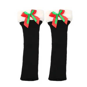 Close-up of black Christmas leg warmers with white fur tops and red-green bows