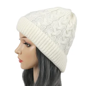 Side view of a cream cable-knit beanie on a mannequin head showing warm texture.