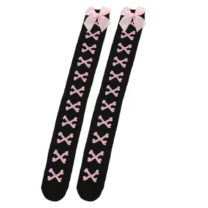 Détail de chaussettes montantes noires avec nœuds roses et motifs d'os
