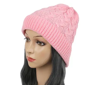 Detail view of a pink cable-knit beanie on a mannequin head showing weave pattern