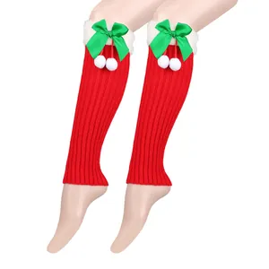 Detail of red knitted Christmas leg warmers with green bows and white pom poms