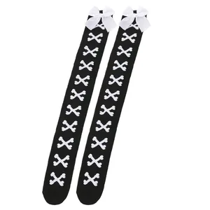 Détail de chaussettes hautes noires avec motif d'os et nœuds blancs